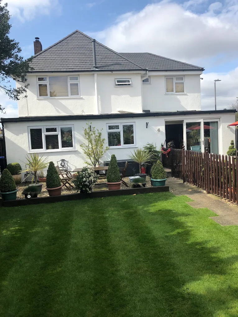 Rear of a white rendered house with a new grey tiled roof, above a striped lawn