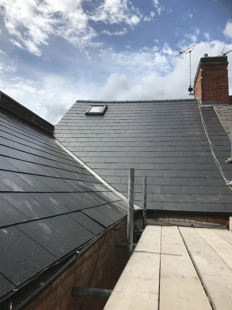 Slate roof with a Velux window and brick chimney, seen from the scaffold boards