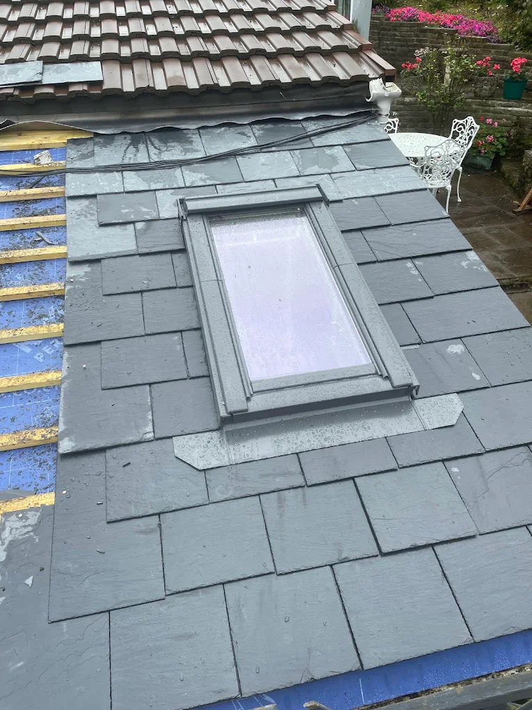 Velux roof window fitted into a new slate roof, with battens showing at the verge